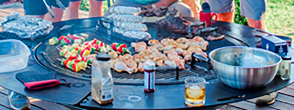 Skewers, chicken and a variety of other food being cooked on a gather grill